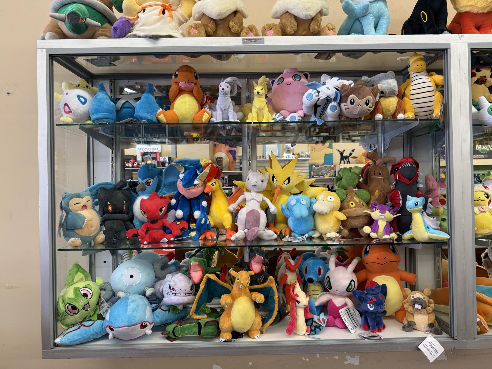 Glass display case with rows of Pokemon plush figures in the store