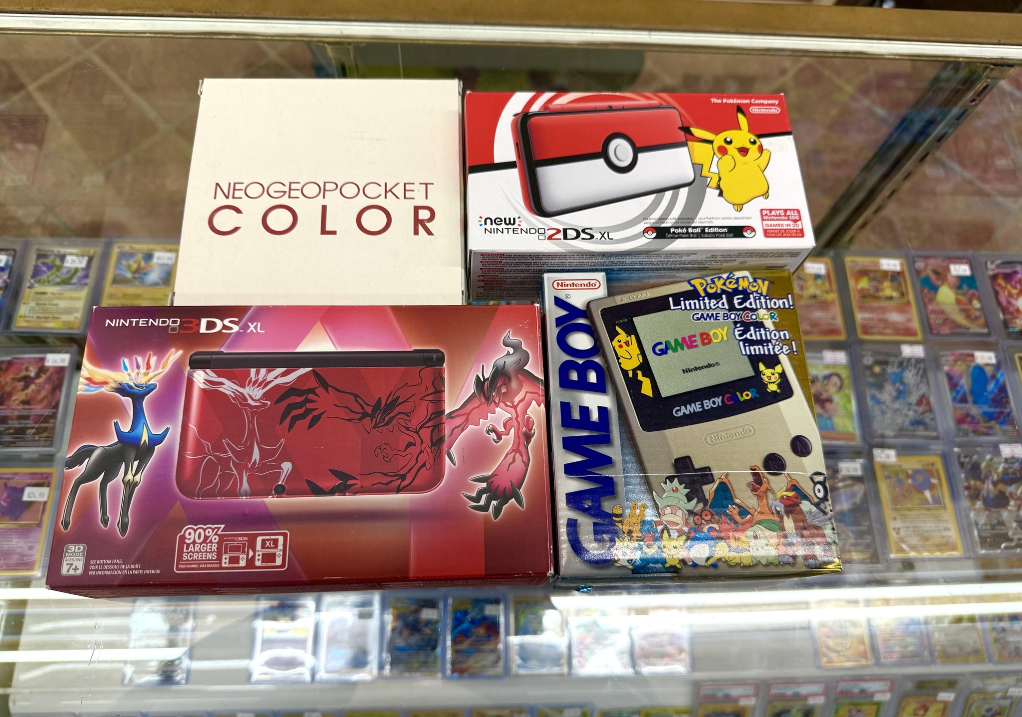 Boxed retro handheld consoles including Nintendo 3DS XL and Game Boy Color Pokemon Edition